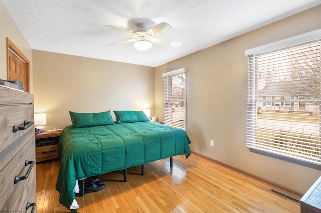 bedroom with ceiling fan, a textured ceiling, and light wood-type flooring