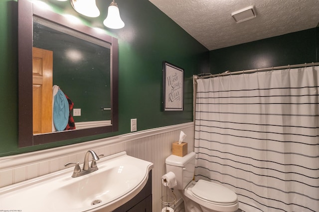 bathroom with vanity, a shower with curtain, toilet, and a textured ceiling