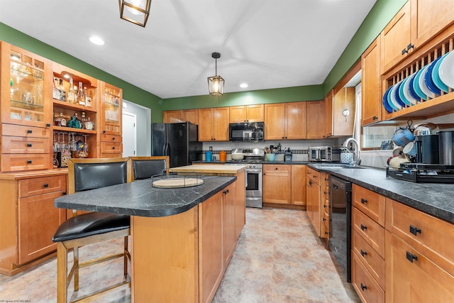 kitchen with sink, a kitchen bar, hanging light fixtures, a center island, and black appliances