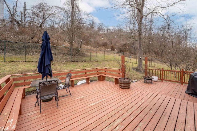 wooden terrace with an outdoor fire pit and a lawn