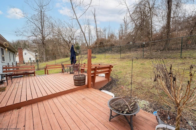 wooden terrace with a fire pit and a lawn