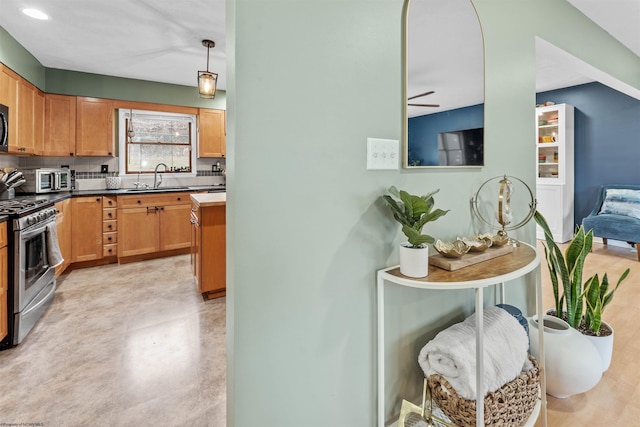 kitchen featuring appliances with stainless steel finishes, sink, backsplash, and decorative light fixtures