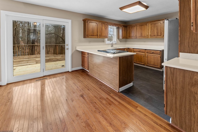 kitchen featuring dark hardwood / wood-style flooring, sink, stainless steel refrigerator, and kitchen peninsula