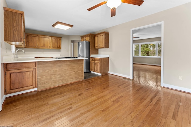 kitchen featuring stainless steel refrigerator, ceiling fan, sink, and light hardwood / wood-style flooring