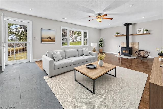 living room with a wood stove, a textured ceiling, and ceiling fan