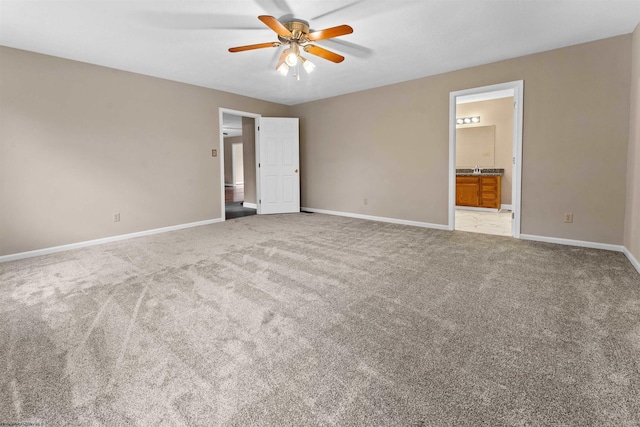 unfurnished bedroom featuring ceiling fan, light colored carpet, and connected bathroom