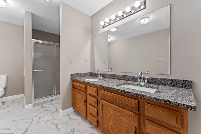 bathroom featuring a shower with door, vanity, and toilet