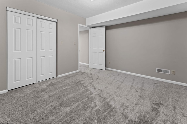 unfurnished bedroom featuring a closet, a textured ceiling, and carpet