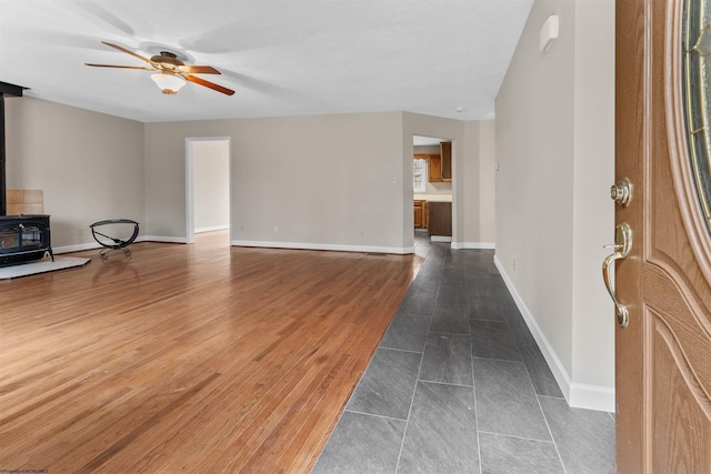 living room with dark hardwood / wood-style flooring, a wood stove, and ceiling fan