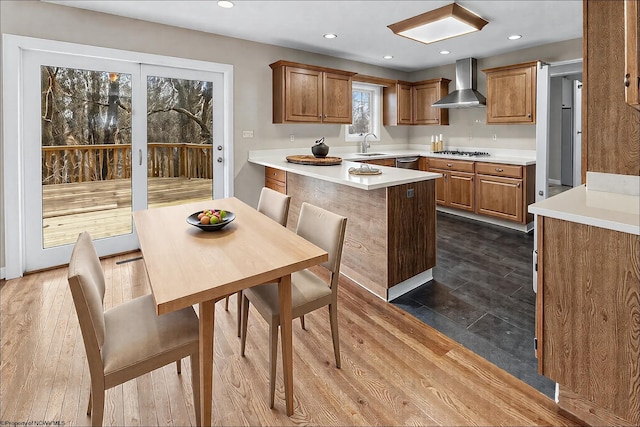 kitchen with wall chimney exhaust hood, sink, a center island, appliances with stainless steel finishes, and dark hardwood / wood-style floors