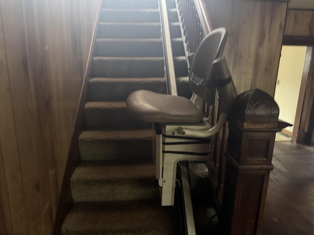 stairway featuring wood walls