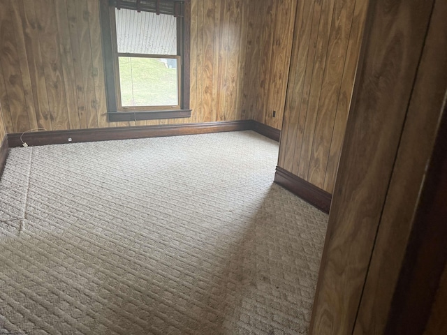 carpeted spare room with wooden walls