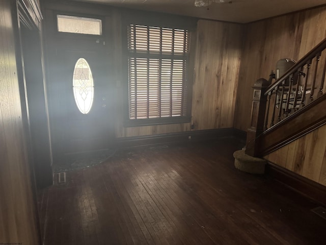 foyer entrance with dark hardwood / wood-style floors and wood walls