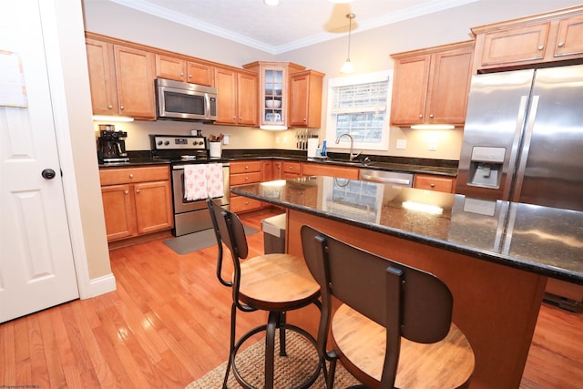 kitchen featuring sink, appliances with stainless steel finishes, hanging light fixtures, a center island, and ornamental molding