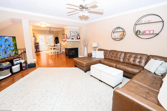 living room featuring hardwood / wood-style flooring, ornamental molding, french doors, and a tile fireplace