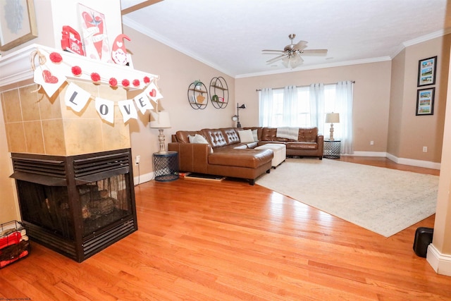 living room with crown molding, ceiling fan, a fireplace, and light hardwood / wood-style flooring