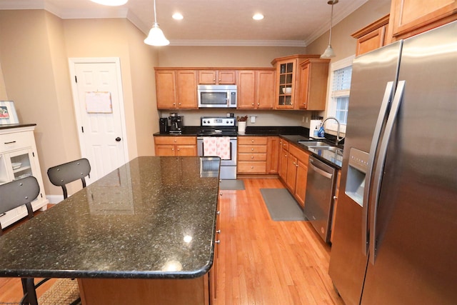 kitchen with sink, appliances with stainless steel finishes, a kitchen breakfast bar, a center island, and decorative light fixtures