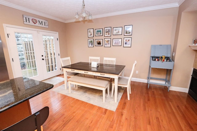 dining space featuring an inviting chandelier, ornamental molding, light hardwood / wood-style floors, and french doors