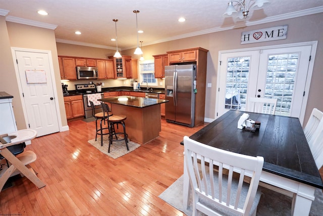 kitchen with a kitchen bar, decorative light fixtures, a center island, light wood-type flooring, and appliances with stainless steel finishes