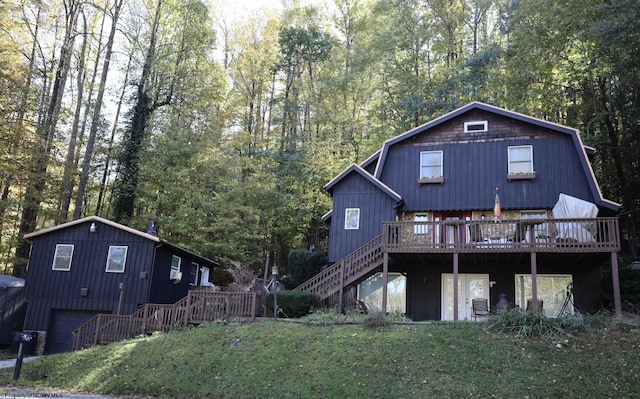 rear view of house with a wooden deck, a garage, and a yard