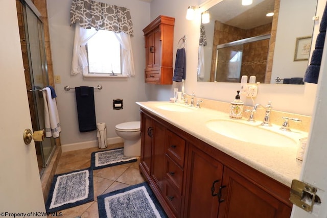 bathroom with tile patterned floors, toilet, a shower with door, and vanity