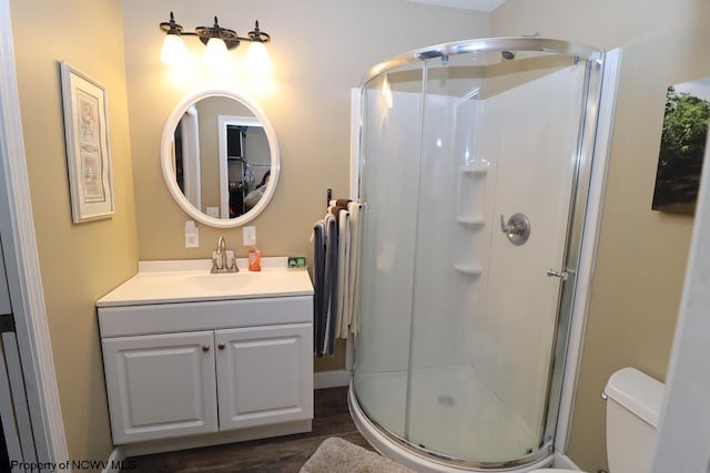 bathroom featuring hardwood / wood-style floors, vanity, toilet, and walk in shower