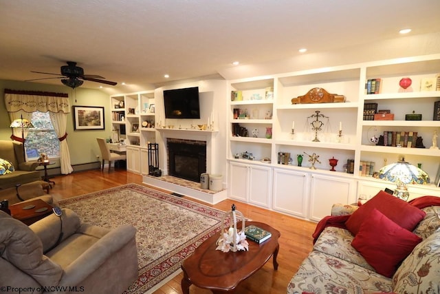 living room with ceiling fan, light hardwood / wood-style floors, and built in features