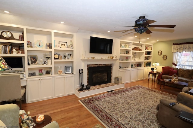 living room featuring ceiling fan, a fireplace, and light hardwood / wood-style flooring