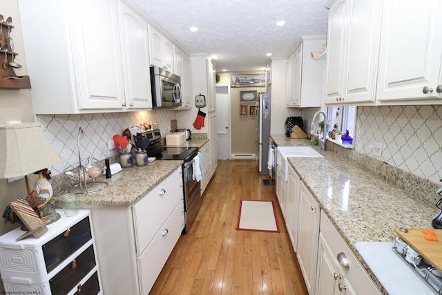 kitchen featuring white cabinetry, light stone counters, and appliances with stainless steel finishes