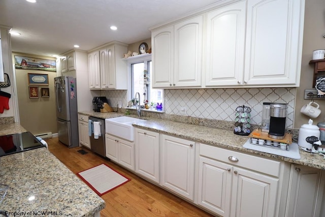 kitchen featuring sink, stainless steel appliances, light stone counters, white cabinets, and light wood-type flooring