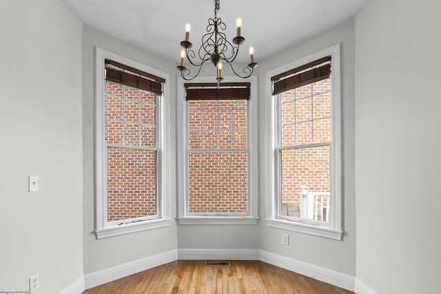 unfurnished dining area with a notable chandelier and light wood-type flooring