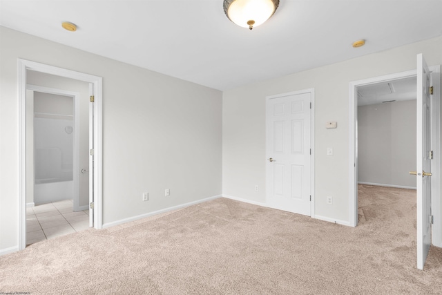 unfurnished bedroom featuring ensuite bathroom and light colored carpet