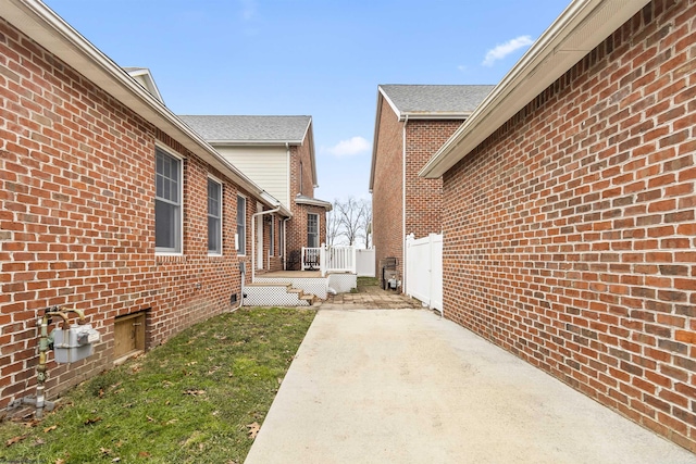 view of side of home with a wooden deck, a yard, and a patio area