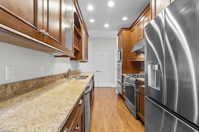 kitchen featuring light stone counters, appliances with stainless steel finishes, sink, and light hardwood / wood-style flooring