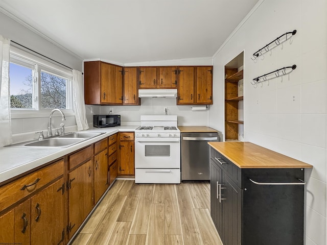 kitchen featuring sink, light hardwood / wood-style flooring, dishwasher, tile walls, and white range with gas cooktop