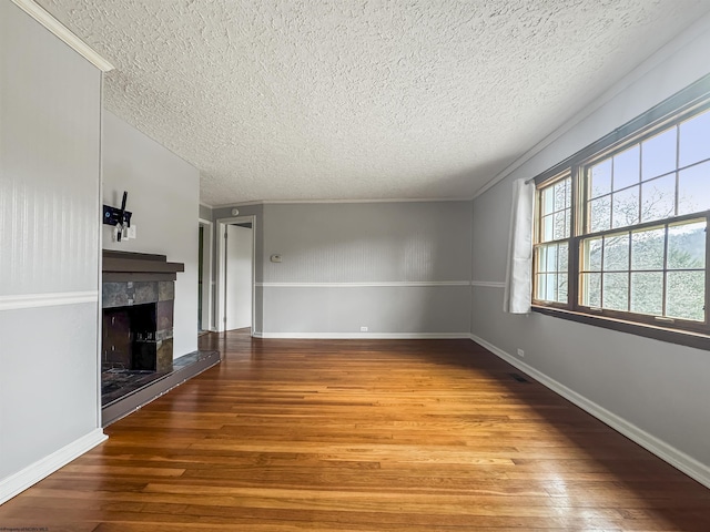 unfurnished living room featuring crown molding, hardwood / wood-style flooring, a fireplace, and a textured ceiling