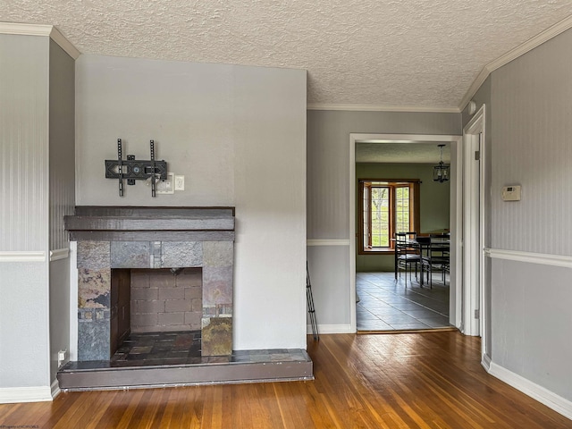 unfurnished living room featuring wood-type flooring, ornamental molding, a fireplace, and a textured ceiling