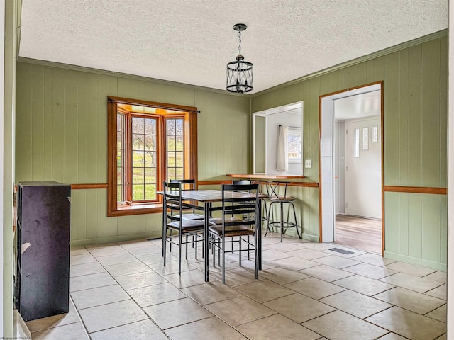 dining room with ornamental molding, an inviting chandelier, and a textured ceiling