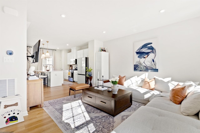 living room featuring sink and light hardwood / wood-style floors