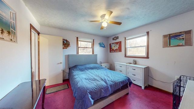 bedroom with ceiling fan, a textured ceiling, and dark colored carpet