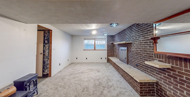 unfurnished living room with a brick fireplace, carpet, brick wall, and a wood stove