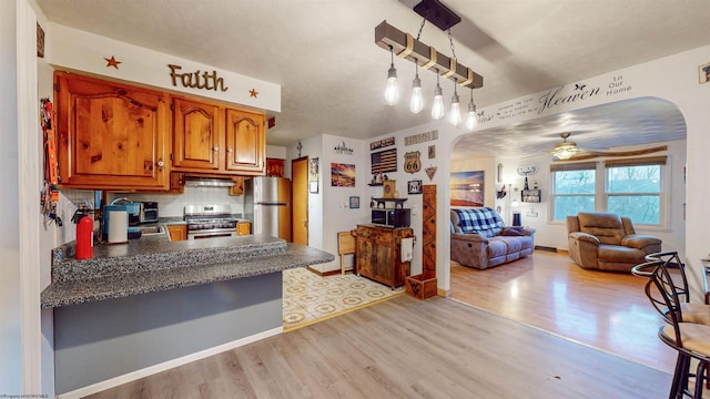 kitchen featuring ceiling fan, appliances with stainless steel finishes, backsplash, and light wood-type flooring