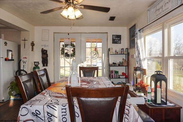 dining area with ceiling fan, dark hardwood / wood-style floors, french doors, and a textured ceiling