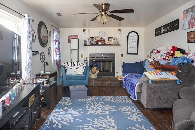 living room featuring a brick fireplace, dark hardwood / wood-style floors, and ceiling fan