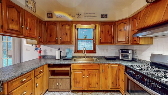 kitchen with tasteful backsplash, gas range, and sink