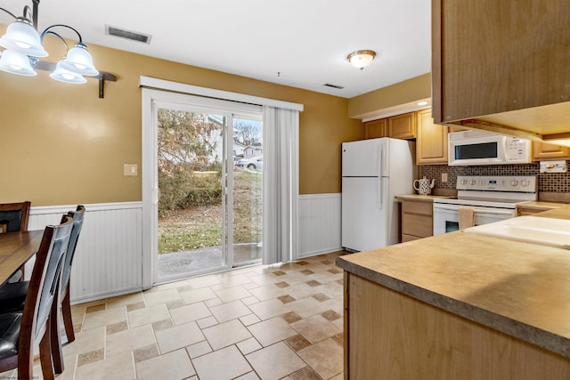 kitchen featuring an inviting chandelier, light brown cabinets, pendant lighting, white appliances, and backsplash