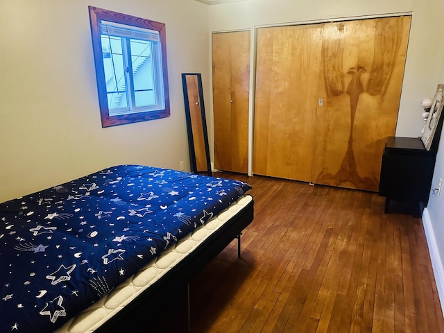 bedroom with two closets and dark wood-type flooring