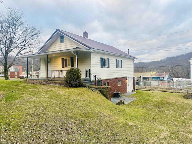 back of house with a yard, central AC unit, and covered porch