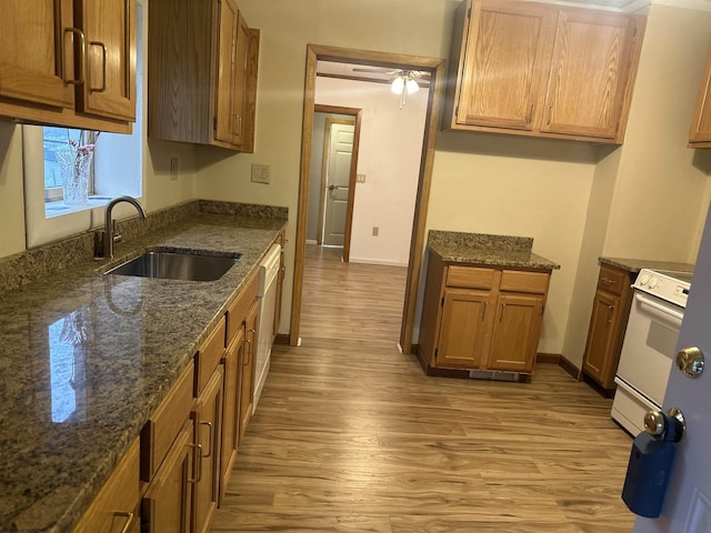 kitchen with sink, white electric range, light hardwood / wood-style floors, and dark stone counters