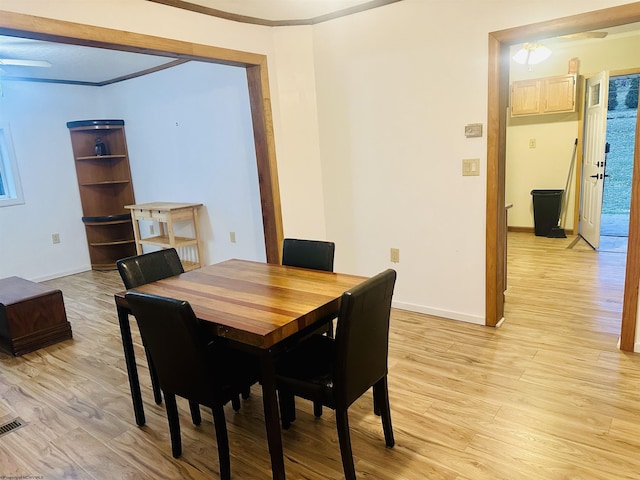 dining area with ornamental molding and light hardwood / wood-style floors